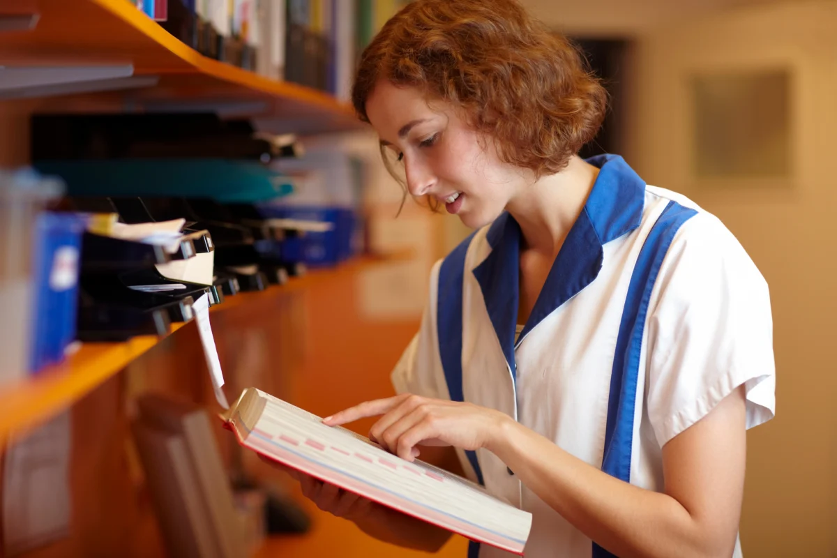 Professionnelle consultant un ouvrage dans une bibliothèque, illustrant l’effet d’autorité associé à l’apparence d’expertise.